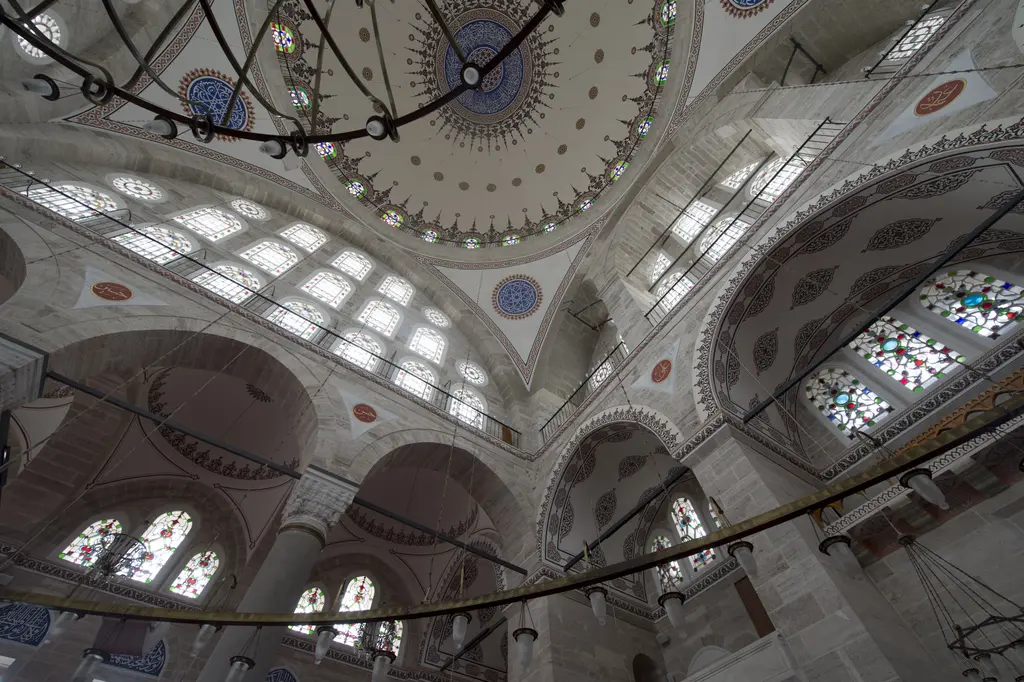 Mihrimah Sultan Camii'nde yukarı bakış; kubbeyi taşıyan büyük sivri kemerler, pandantifler, kemer dolgusundaki pencere katları ve kubbe eteği.