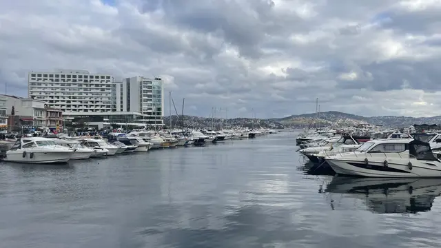 Tarabya Marinası; sakin suda demirli motorlu tekneler, rıhtım, kıyıdaki binalar ve uzakta otel yapısı.