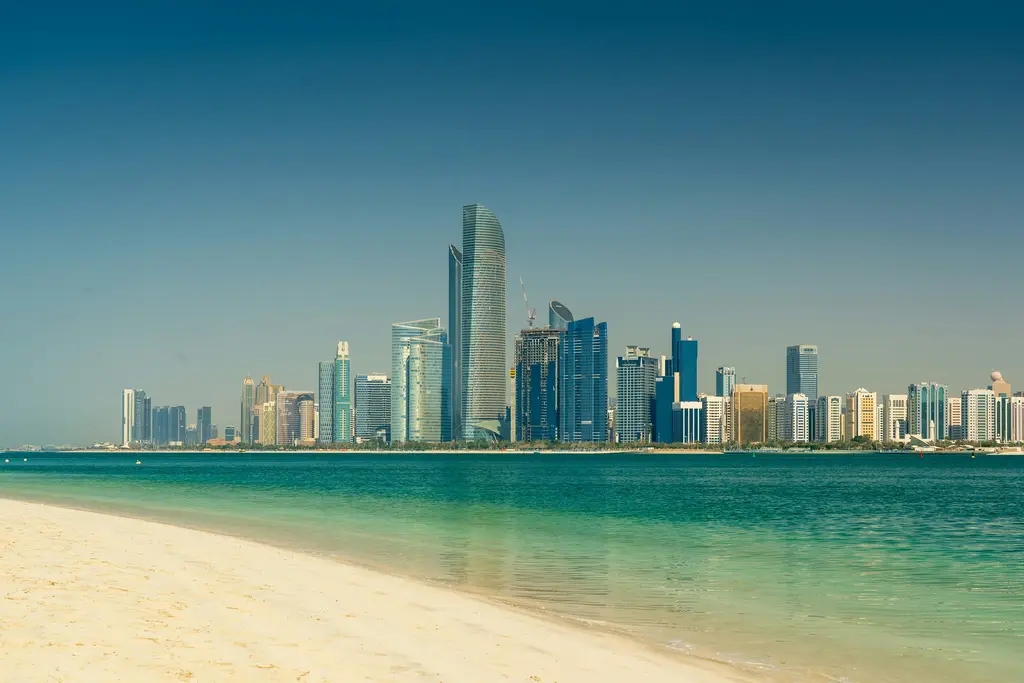 Abu Dabi Corniche'ten şehir silueti; deniz kıyısı, palmiyeler ve arkadaki gökdelenler.