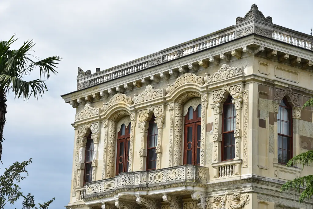 Küçüksu Kasrı'nın köşe cephesi; balkonlu üst kat, kemerli pencereler, yoğun taş kabartmalar ve çatıda korkuluk.