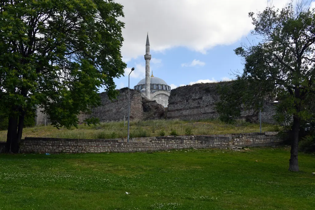 Mihrimah Sultan Camii surların dışından; önde kara surlarının uzun taş duvarı, duvarın üstünden yükselen kubbe ve ince minare.