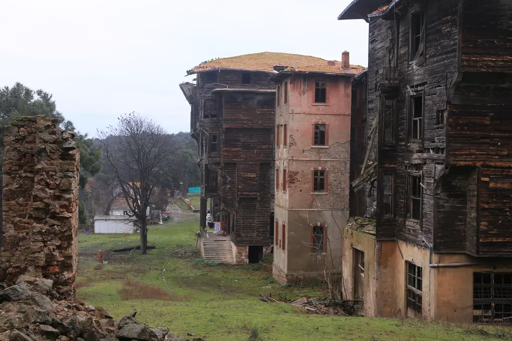 Büyükada Rum Yetimhanesi; yüksek ahşap kanat, yanında pembe sıvalı ve tuğla yapı ile çimenlik.