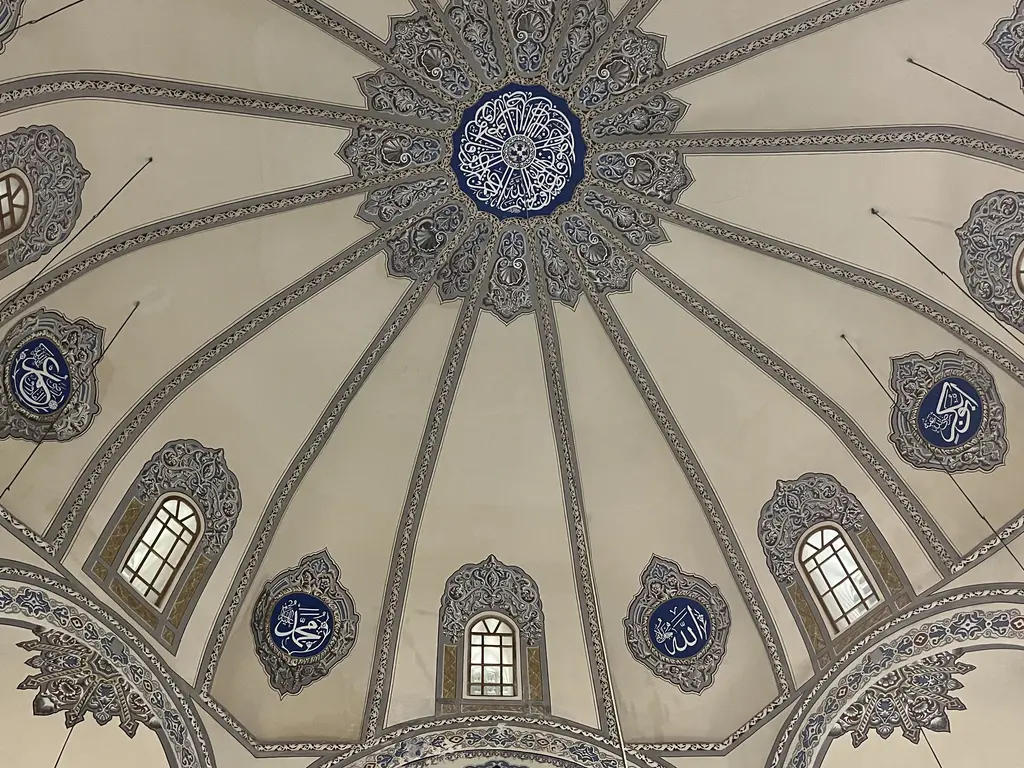 Küçük Ayasofya Camii'nin kubbesine alttan bakış; krem zeminde merkezden ışınlanan on altı gri kaburga, ortada lacivert göbek madalyonu ve kaburgalar arasında hat madalyonları.
