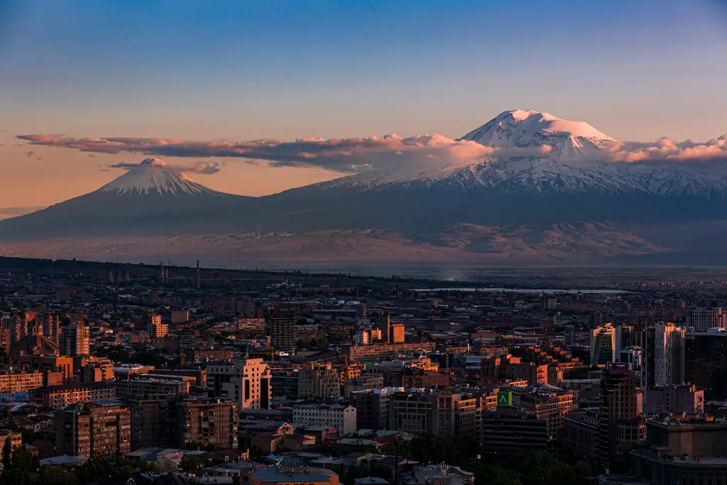Ermenistan'ın başkenti Erivan'ın gün batımı manzarası; şehrin ardında yükselen Büyük ve Küçük Ağrı Dağı'nın (Ararat) karlı çift zirvesi.