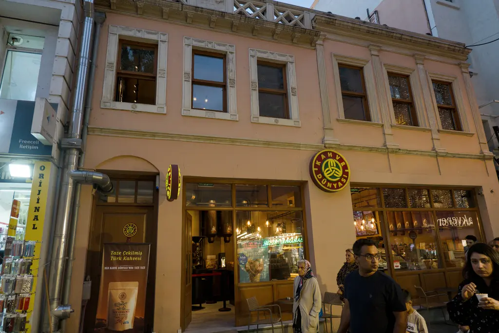 Kadıköy Çarşısı'nda tarihî bina; krem rengi cephe, sıralı pencereler, zemin katta dükkânlar ve yürüyenler.