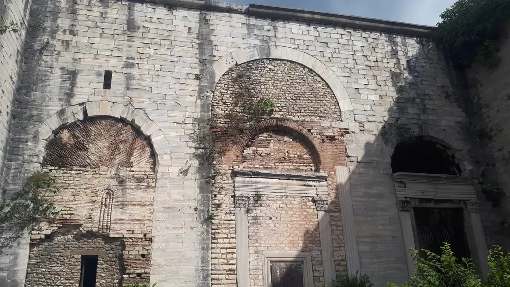 Altın Kapı'nın üç kemerli nişine yakın kadraj; tuğla ile taşın almaşık örgüsü, mermer söveli kapılar, kemer içlerinde yelpaze biçimli tuğla dizilişi ve üstte bitkilenme.