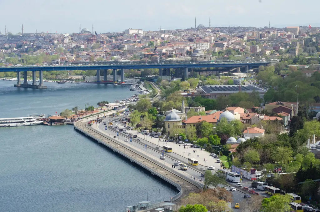 Pierre Loti Tepesi'nden Haliç; kıyı yolu, iskele, ağaçlar arasındaki evler, Haliç'i geçen köprü ve karşı yamaçtaki kent.
