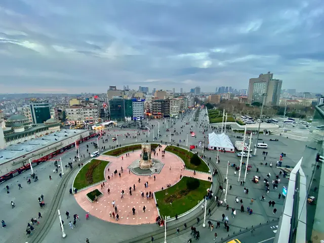 Yukarıdan Taksim Meydanı; ortada yeşil çimlerle çevrili pembe taş döşeli alan ve anıt, çevresinde yürüyen kalabalık, arkada Beyoğlu'nun binaları.