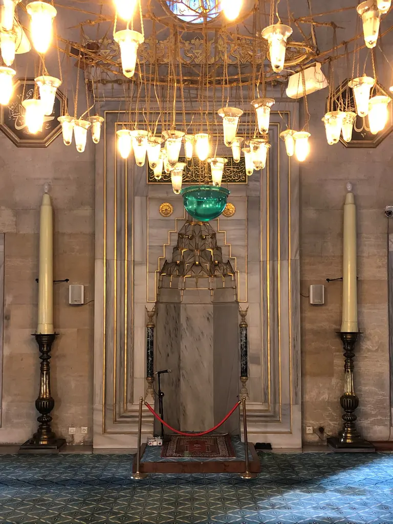 Şişli Camii'nin mihrabı; mukarnaslı mermer niş, iki yanda şamdanlar, üstte avize ve yanlarda pencereler.