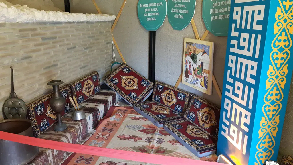 Kültür evlerinden birinin içi; renkli desenli halılar, alçak sedir, bakır kaplar, duvarda işlemeli kumaşlar ve tavanda sarı bordür.