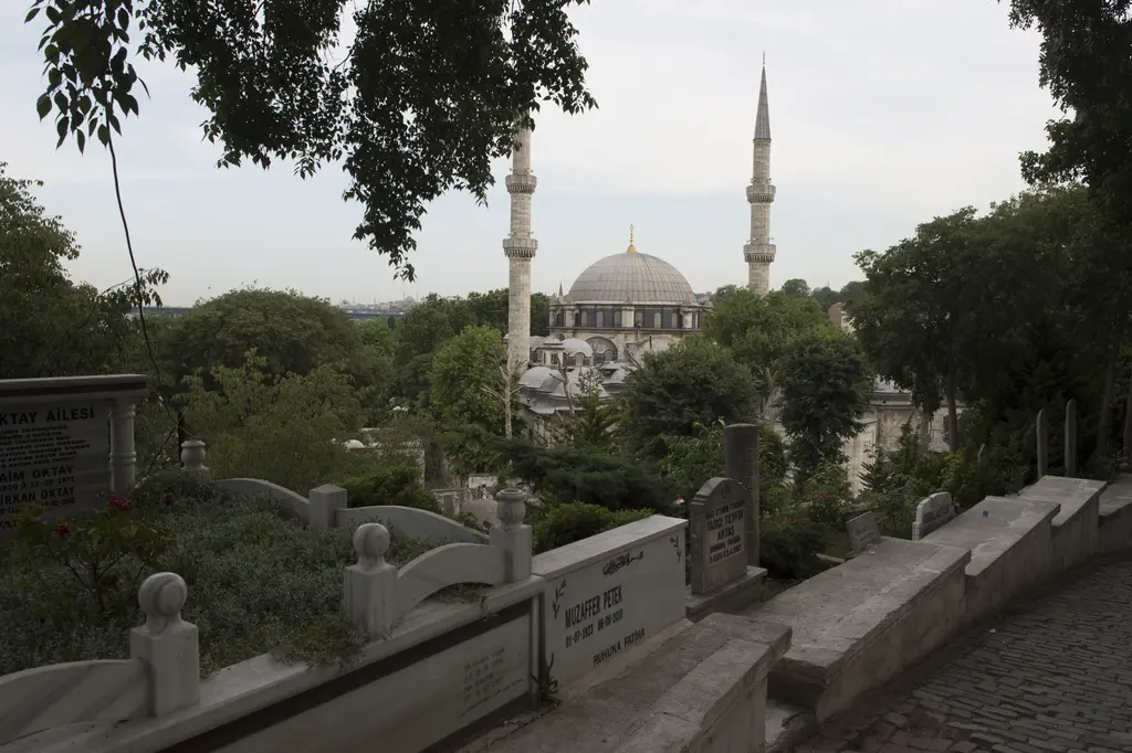 Eyüp Mezarlığı'ndan Eyüp Sultan Camii; yamaçtaki kabirler, mermer mezar taşları, ağaçların arasında kubbe ve iki minare.