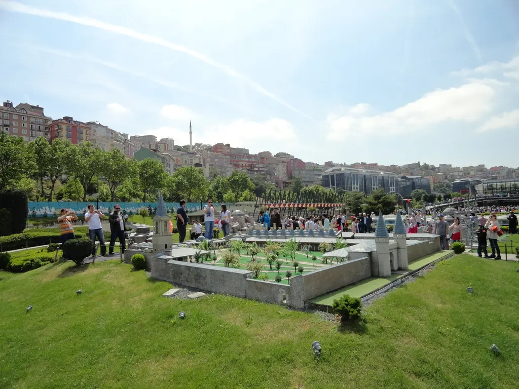 Miniatürk'te Topkapı Sarayı maketi; surlar, Bâbüsselâm'ın iki kulesi, küçük ağaçlı avlu ve arkada fotoğraf çeken ziyaretçiler.