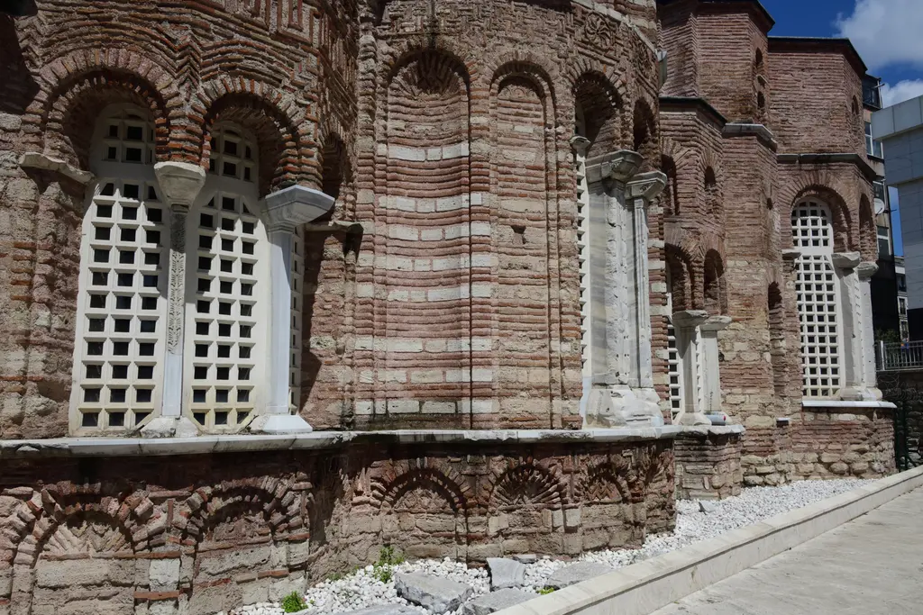 Fenari İsa Camii'nin doğu cephesinde beyaz mermer kafes pencereler; ince mermer sütunçeler, tuğla taş almaşık duvar ve zeminde restorasyondan kalan beyaz moloz.