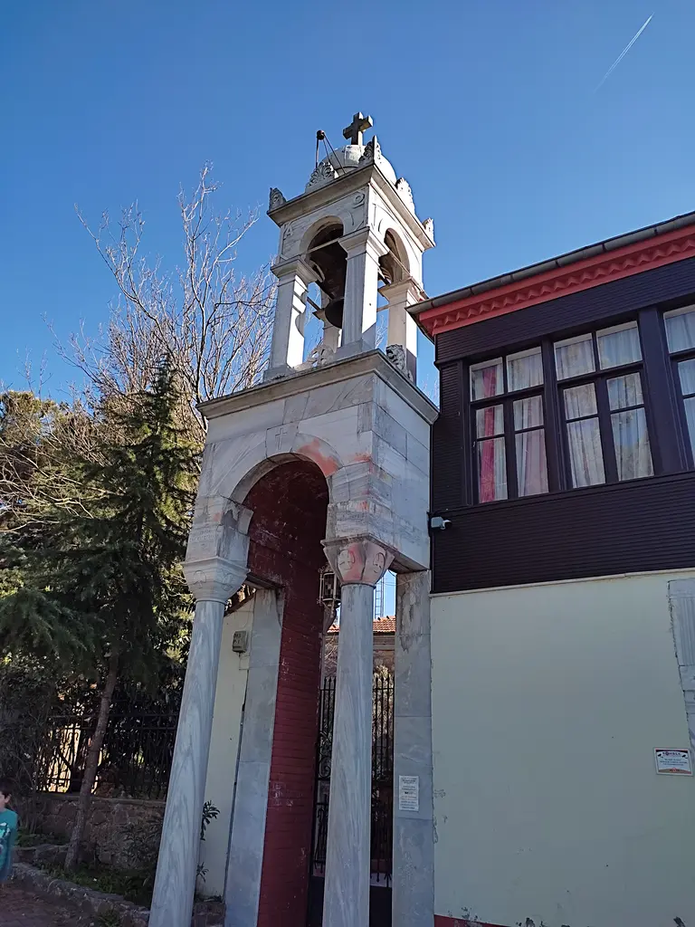 Aya Yorgi Manastırı; beyaz çan kulesinin yanında koyu ahşap çerçeveli pencereler ve kırmızı saçaklı çıkma.