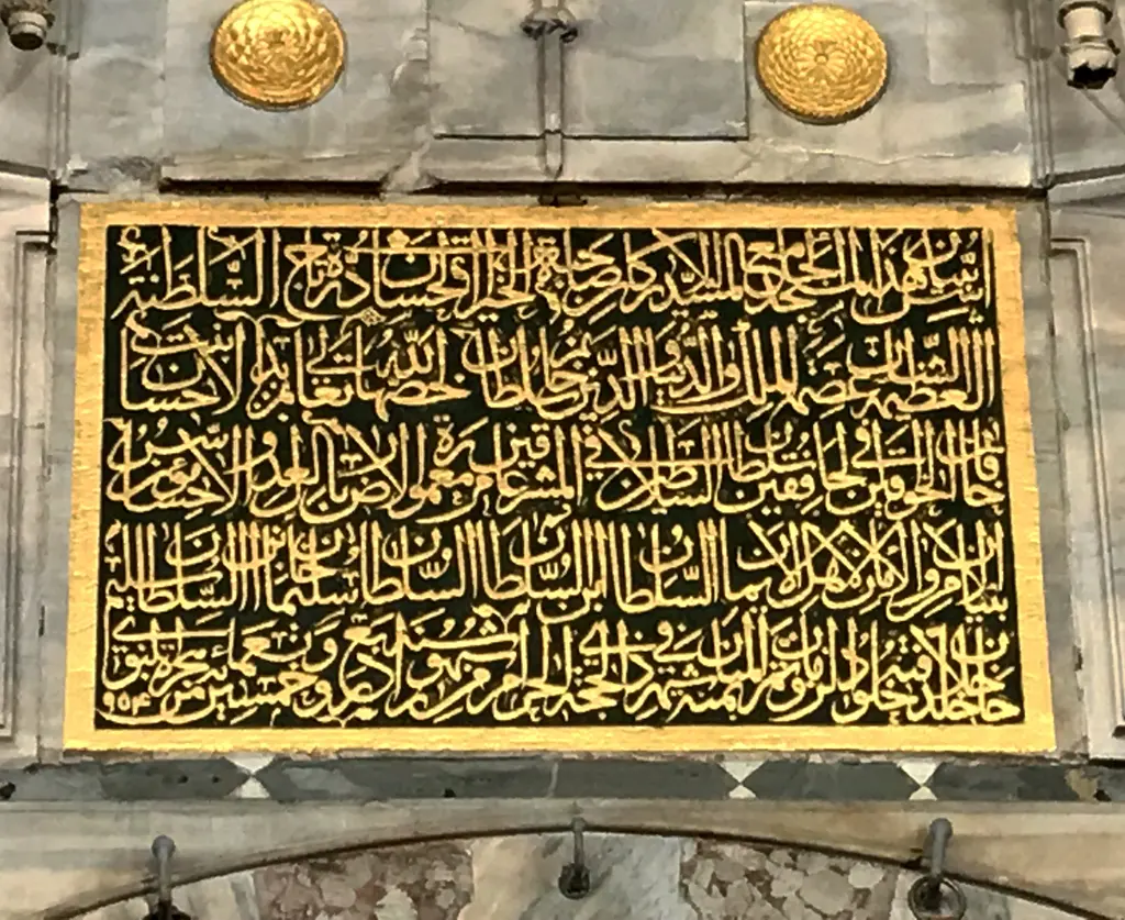 Mihrimah Sultan Camii'nin kitabesi; altın yaldızlı celi yazı, siyah zemin ve üstte iki madalyon.