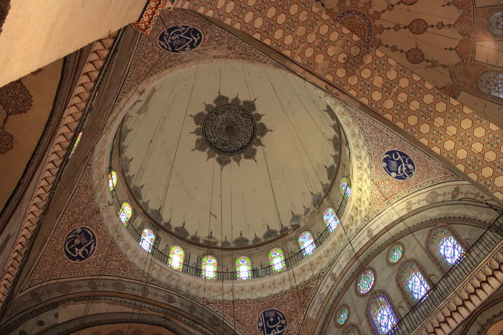 Kubbe ile taşıyıcıları içeriden; pandantifler, kemer alınlıkları, renkli camlı pencere sıraları ve boyalı madalyonlar.