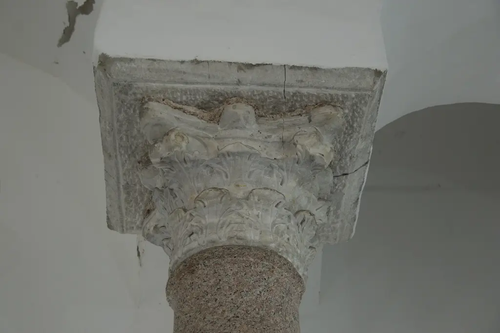 Bodrum Camii'nin alt yapısında devşirme bir mermer sütun başlığı; akantus yaprakları, köşe volütleri, üstte çatlamış abaküs bloğu, altta pembe granit gövde.