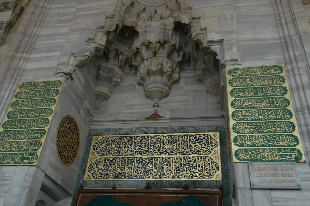 Mahmut Paşa Camii'nin mermer taçkapısı; mukarnaslı kavsara, altta altın harfli Arapça kitabe ve iki yanda yeşil zeminli çok satırlı yazı panoları.