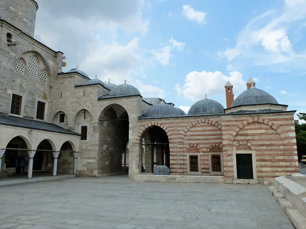 Mihrimah Sultan Camii avlusunun doğu yanı; revak kemerleri, taş ile tuğlanın sıra sıra örüldüğü duvarlar, kurşun kaplı kubbeler ve minarenin dibi.