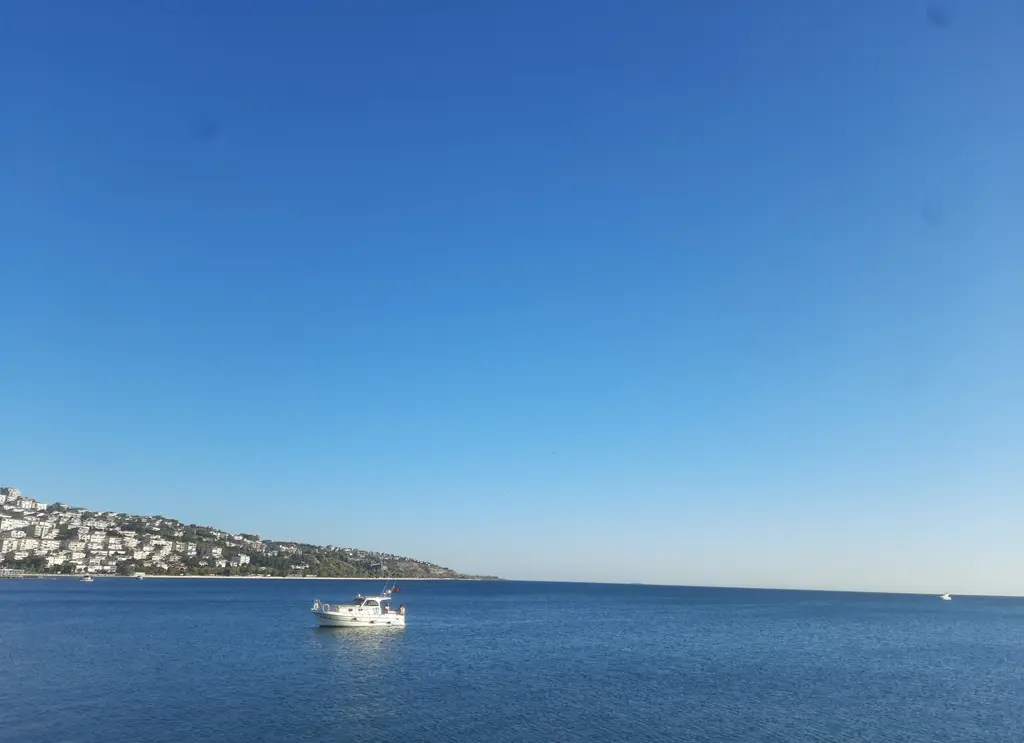 Büyükçekmece'den Marmara Denizi; masmavi deniz, açıkta küçük bir tekne ve uzakta yamaca kurulu yerleşim.