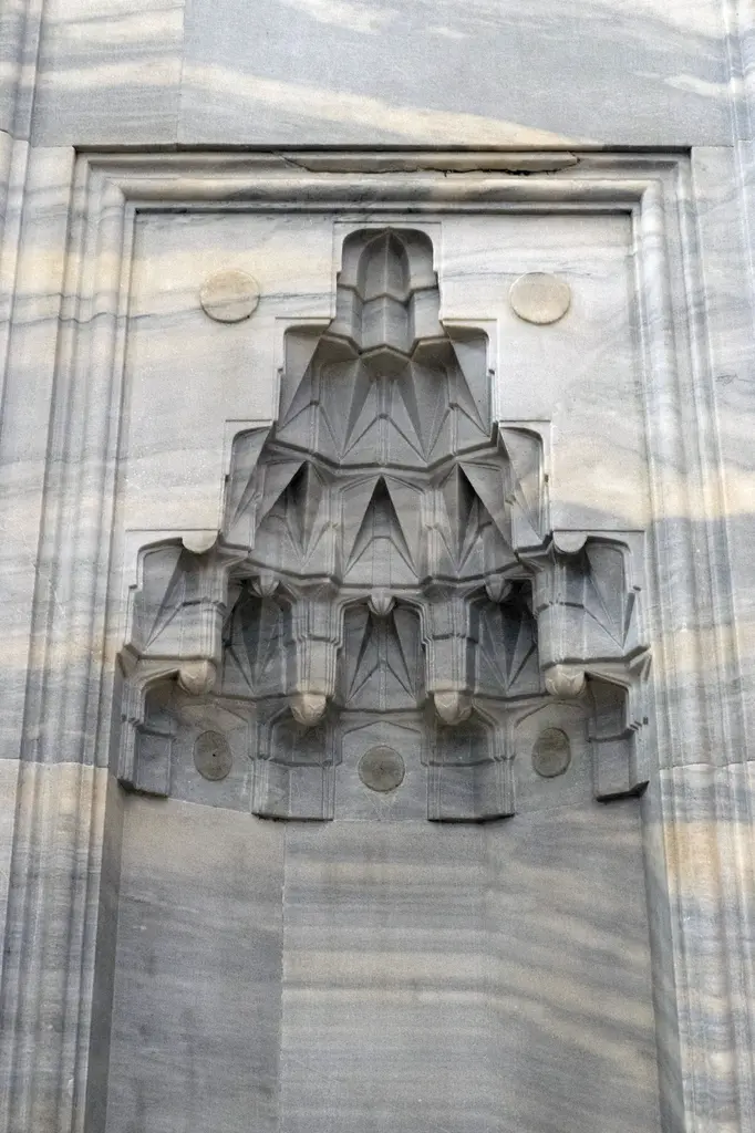Yavuz Sultan Selim Camii'nde avlu duvarındaki dış mihrap; sade mermer niş ve üstünde kademe kademe sarkan mukarnas kavsara.