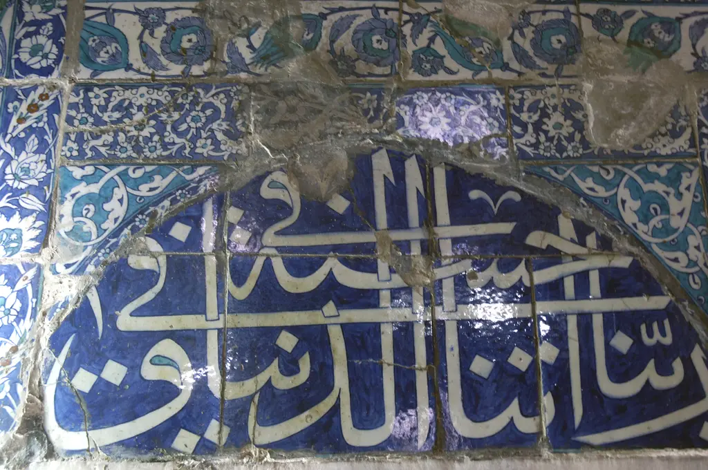 Çinili Camii'nde çini yazı; lacivert zemin üzerine beyaz Arapça harfler, üstte kemer ve çatlak sır.