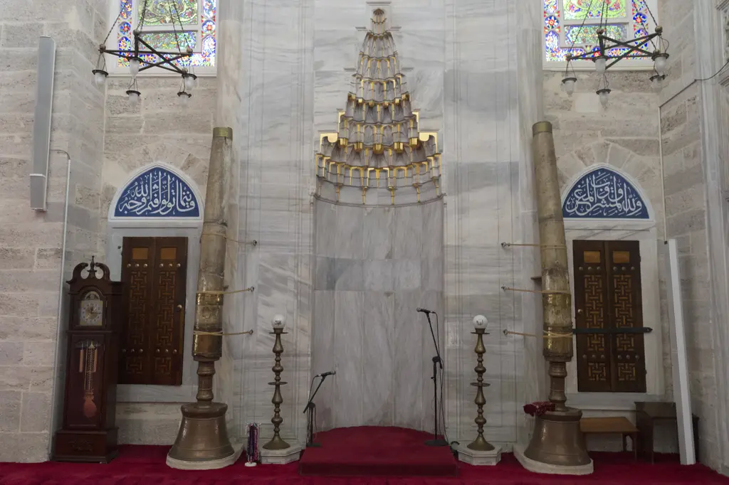 Mihrimah Sultan Camii'nin mihrabı; mukarnas kavsaralı mermer niş, iki yanında hat madalyonları, önünde büyük şamdanlar ve ahşap kanatlı kapılar.