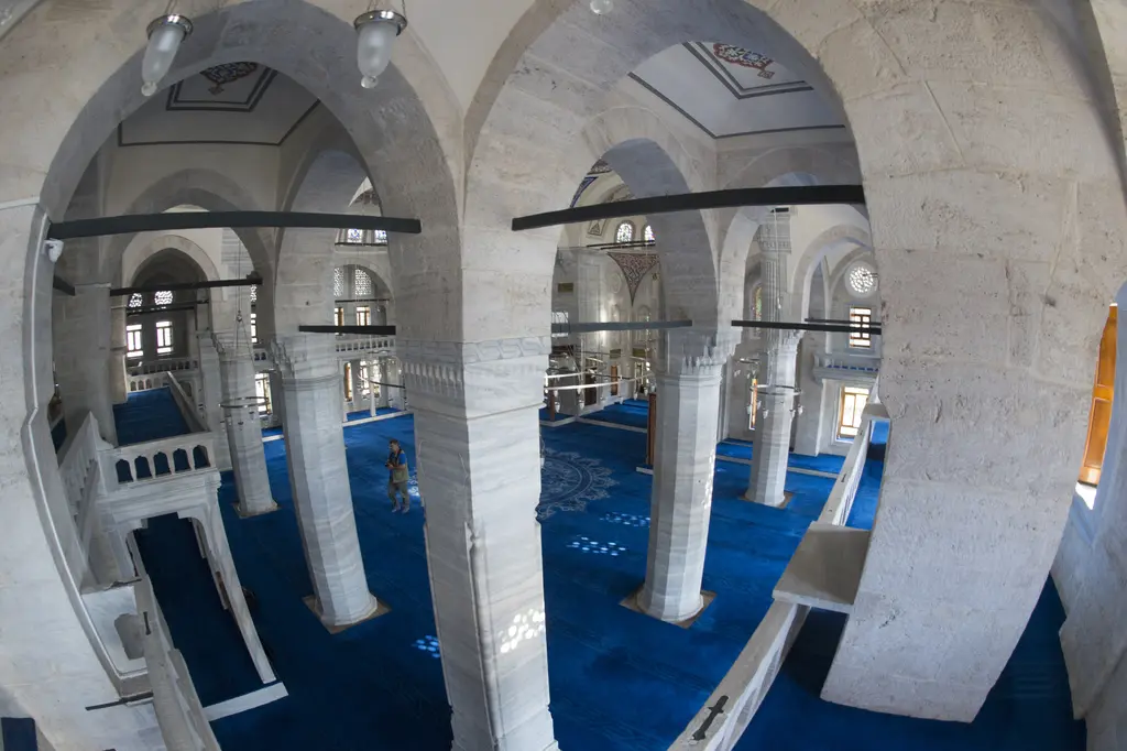Azapkapı Sokullu Mehmed Paşa Camii'nde mahfil katından bakış; kemerler arasından görülen harim, payeler, mavi halı ve kalem işli kubbe.