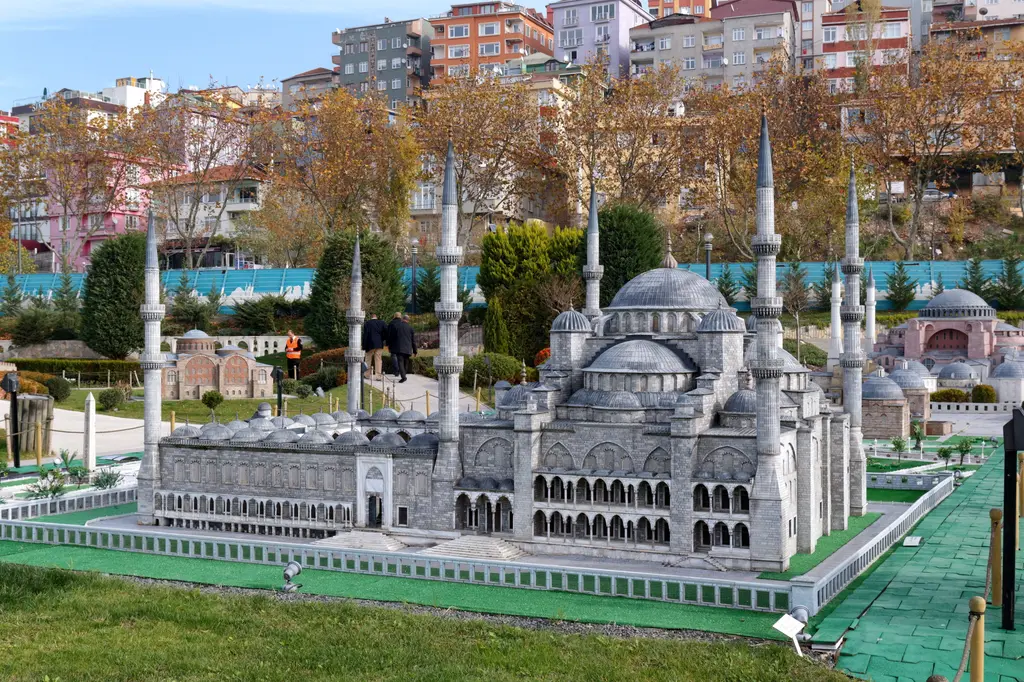 Miniatürk'te Sultanahmet Camii maketi; altı minare, gri kubbeler, yeşil zeminli avlu, sağda Ayasofya maketinin bir kısmı ve sonbahar ağaçları.