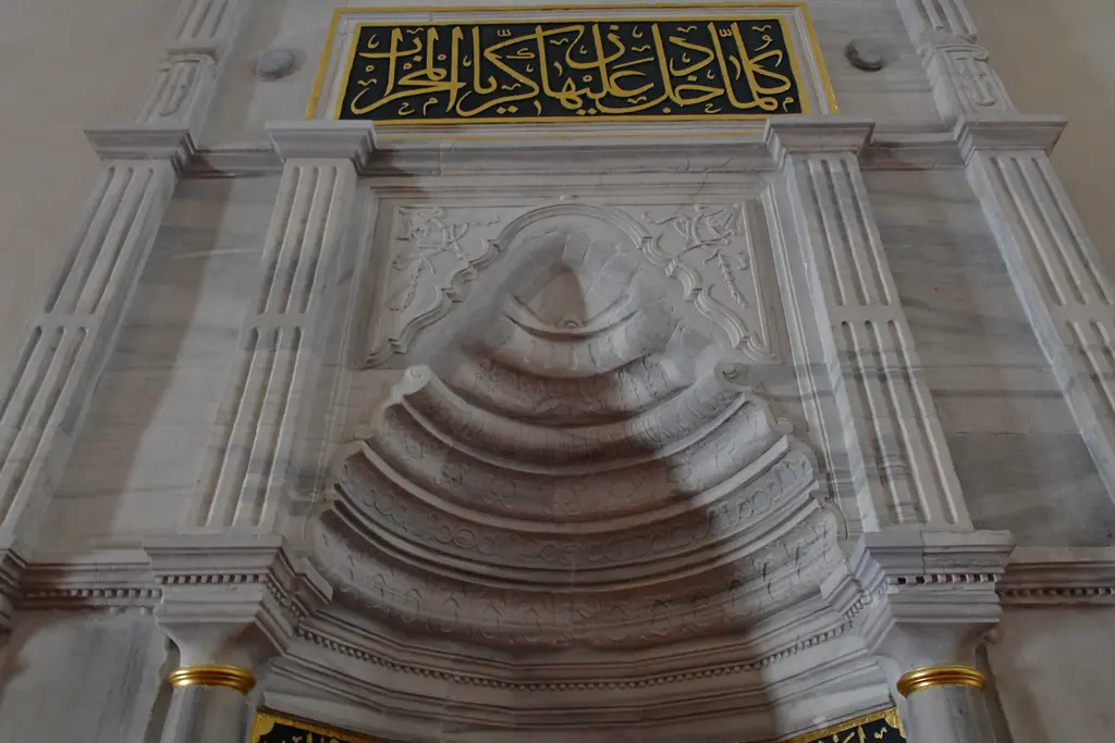 Mahmut Paşa Camii'nin mermer mihrabı; sarkıtlı kavsara, iki yanda yivli sütunçeler, üstte altın harfli yeşil zeminli yazı şeridi.