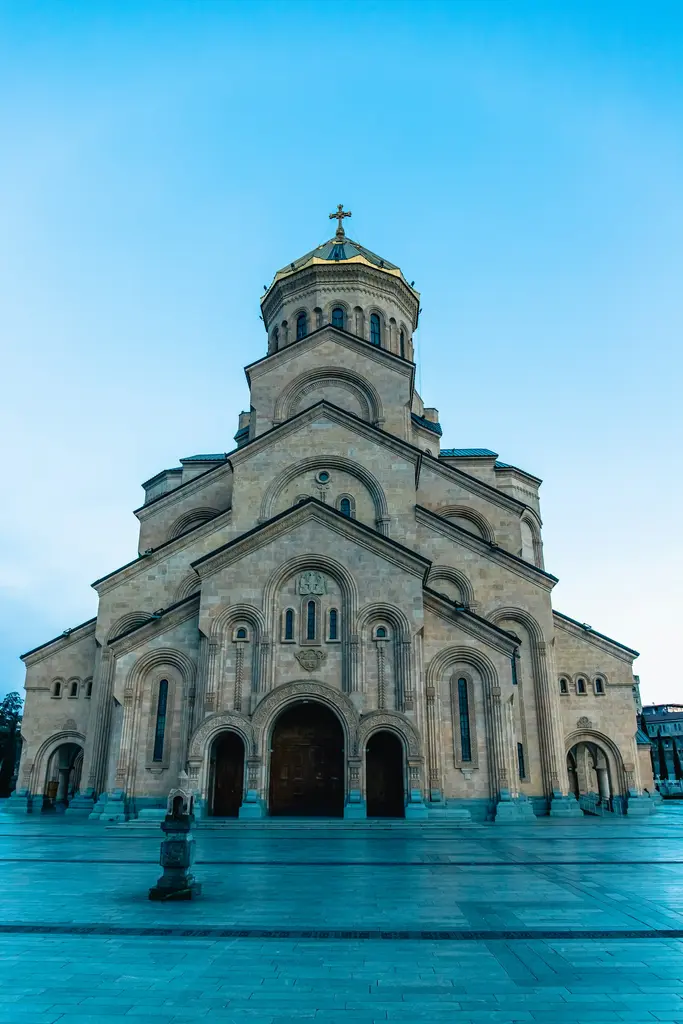 Mtskheta'da Svetitskhoveli Katedrali'nin taş kütlesi ve çevresini saran surlar; arkada iki nehrin birleştiği vadi ve dağlar.