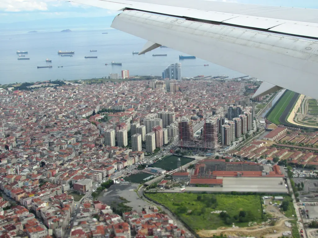 Uçaktan Zeytinburnu; kırmızı çatılı sık yapı dokusu, sağda yeşil pistleriyle hipodrom, solda gemilerin demirlediği Marmara Denizi ve ufukta adalar.