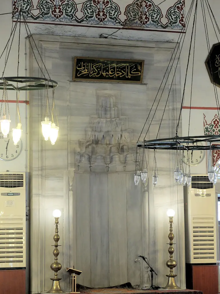 Murat Paşa Camii'nin mihrabı; beyaz mermer niş, mukarnaslı yaşmak, üstte yazı levhası ve iki yanında büyük şamdanlar.