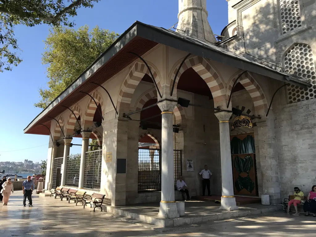 Mihrimah Sultan Camii'nin son cemaat yeri; ahşap çatı altında sıralanan sütunlar, kırmızı halılar ve oturan ziyaretçiler.