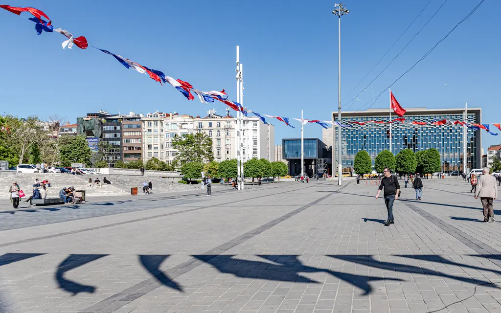 Taksim Meydanı'nın geniş taş zemini; solda Gezi Parkı'na çıkan merdivenler ve ağaçlar, sağda Atatürk Kültür Merkezi.