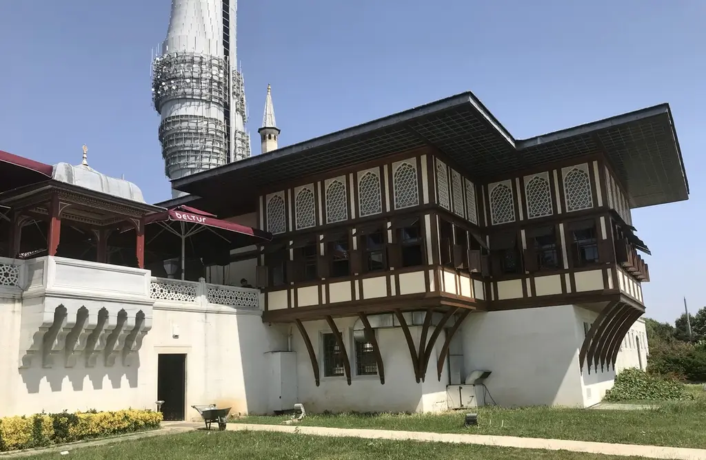 Küçük Çamlıca'da Cihannüma Köşkü; ahşap saçaklı, geniş pencereli yapı, beyaz duvar ve arkada kulenin gövdesi.