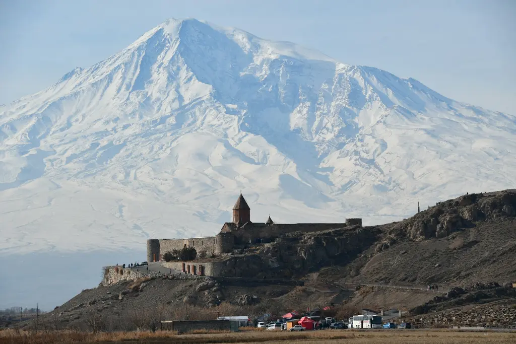 Ermenistan'da Ağrı Dağı'nın (Ararat) karlı zirvesinin eteğindeki tepeye kurulu Hor Virap Manastırı; surlarla çevrili taş yapı ve kırmızı konik kubbeli kilise.