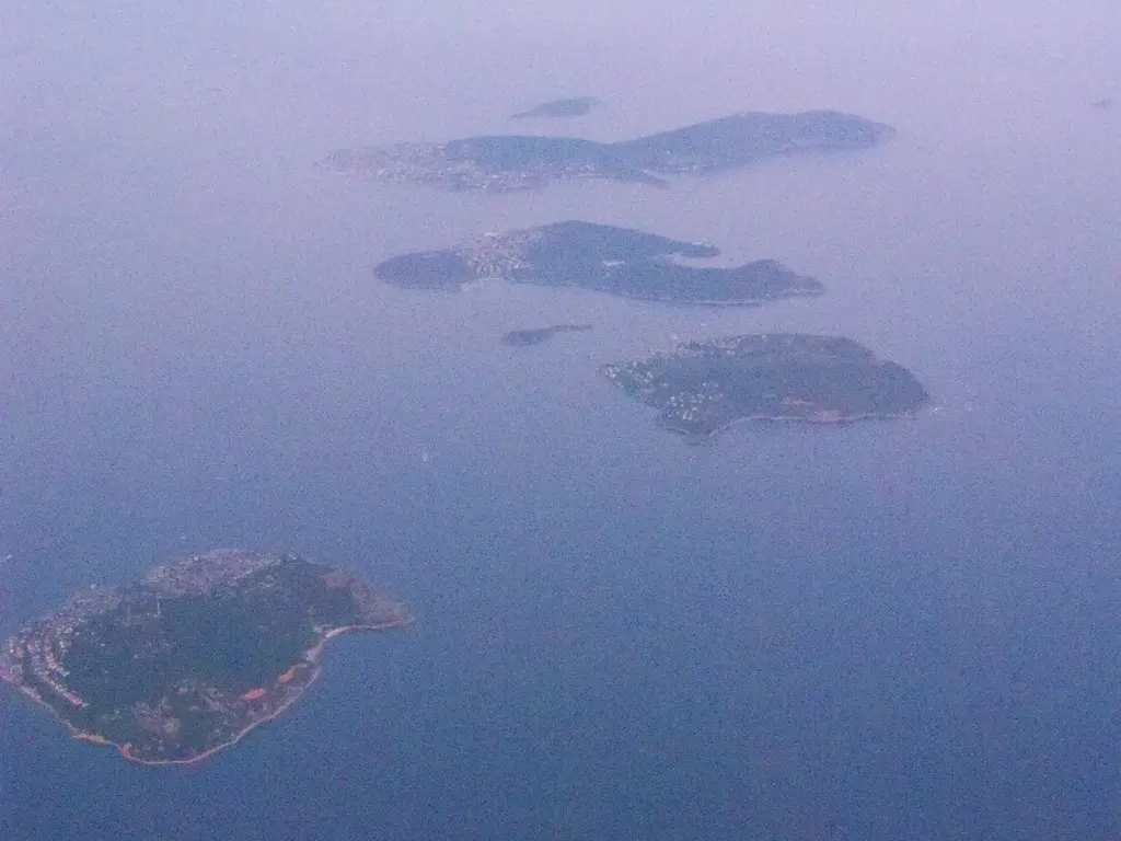 Uçaktan Adalar; puslu Marmara'nın ortasında dizilen yeşil adalar ve aralarındaki sakin deniz.