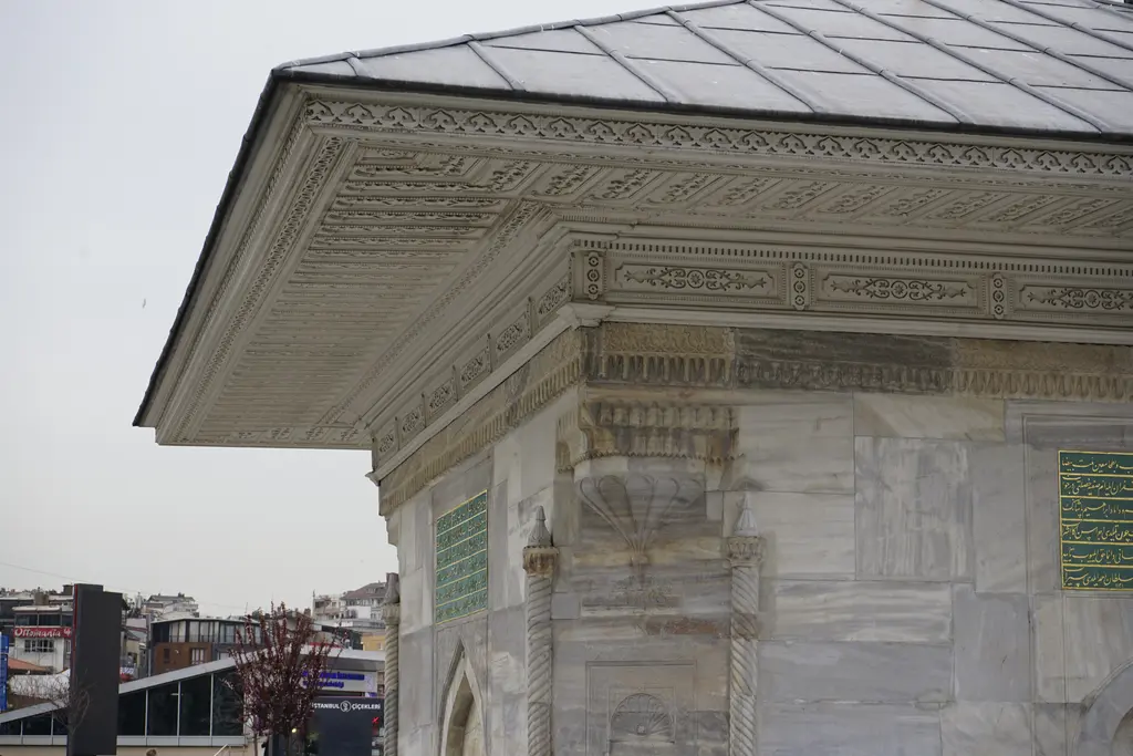 III. Ahmed Çeşmesi'nin saçağı; oymalı ahşap saçak, kabartmalı korniş, kitabe levhası ve kurşun çatı.
