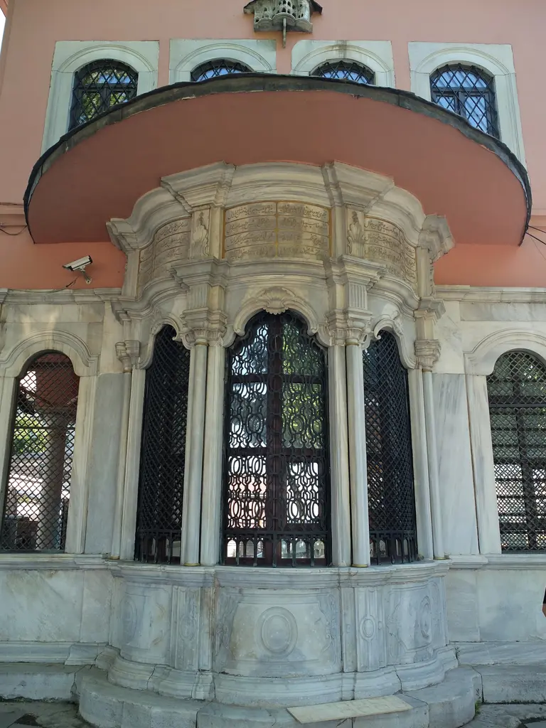 Şah Sultan Sebili'nin cephesi; dalgalı kemerli şebekeli pencereler, mermer kabartmalar, kitabe ve geniş saçak.
