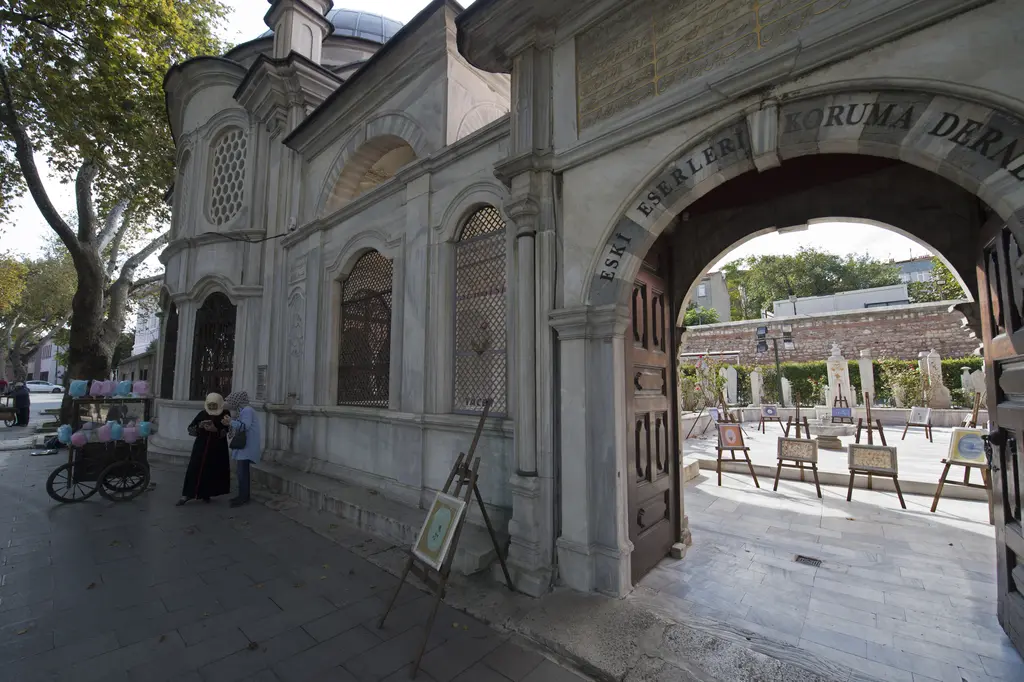 Şah Sultan Külliyesi'nin avlu kapısı; yuvarlak kemerli mermer kapı, açık ahşap kanatlar, solda türbe ve içeride avlu.