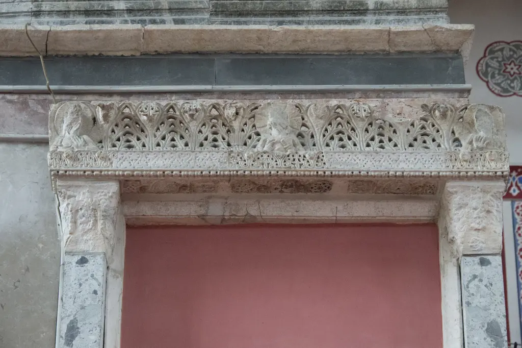 Kalenderhane Camii'nde kapı üstündeki beyaz mermer lento; delikli bitkisel oyma friz, madalyonlar içinde yıpranmış büst kabartmaları ve inci dizili bordür.