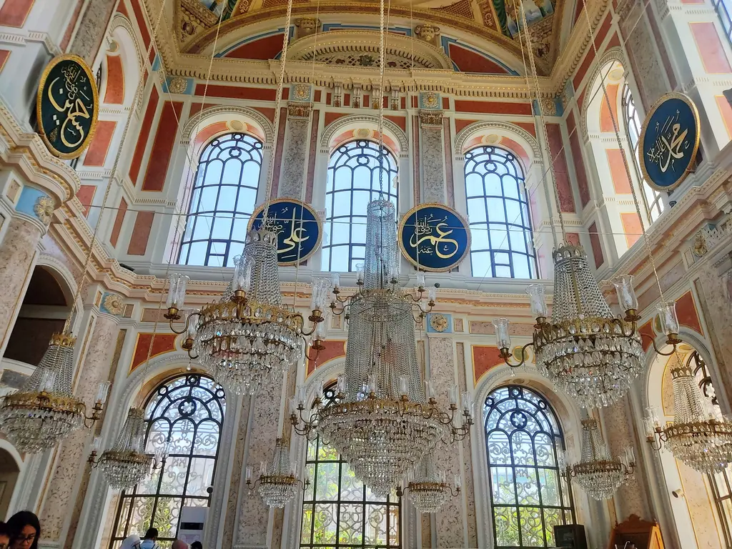 Ortaköy Camii'nin harimi; iki sıra büyük kemerli pencere, kristal avizeler, yuvarlak hat levhaları ve pembe tonlu duvarlar.