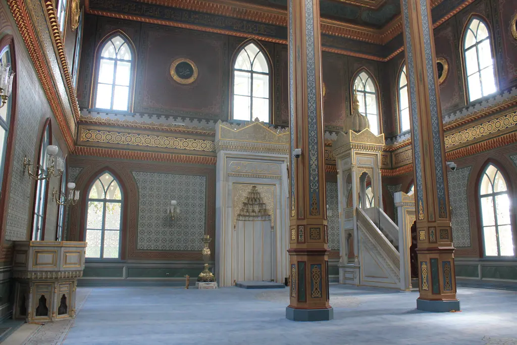 Yıldız Hamidiye Camii'nde mihrap ve minber; beyaz mermer mihrap, sivri kemerli pencereler ve iki ahşap kolon.