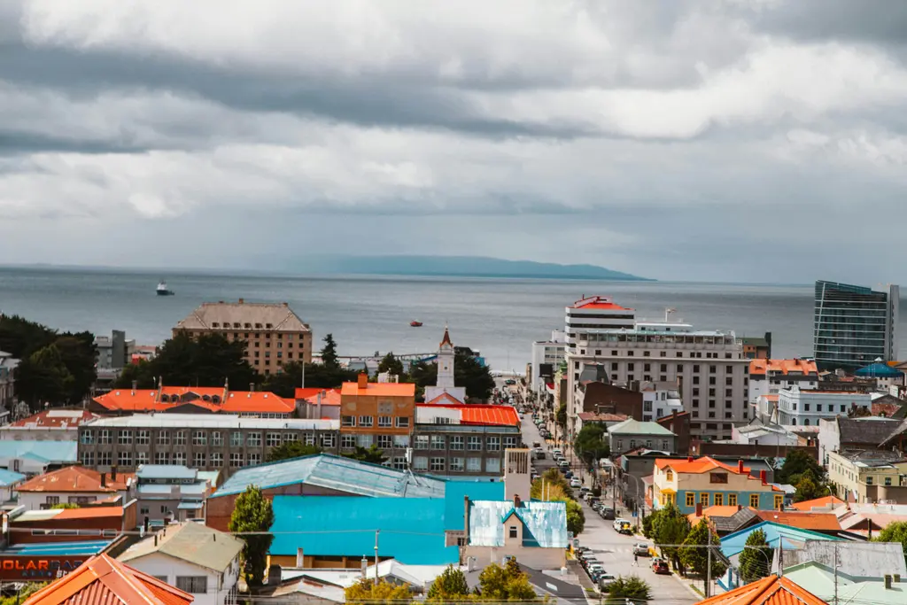 Punta Arenas; kırmızı ve turkuaz çatıların Magellan Boğazı'na doğru alçaldığı kent ve gri bulutlu gökyüzü.