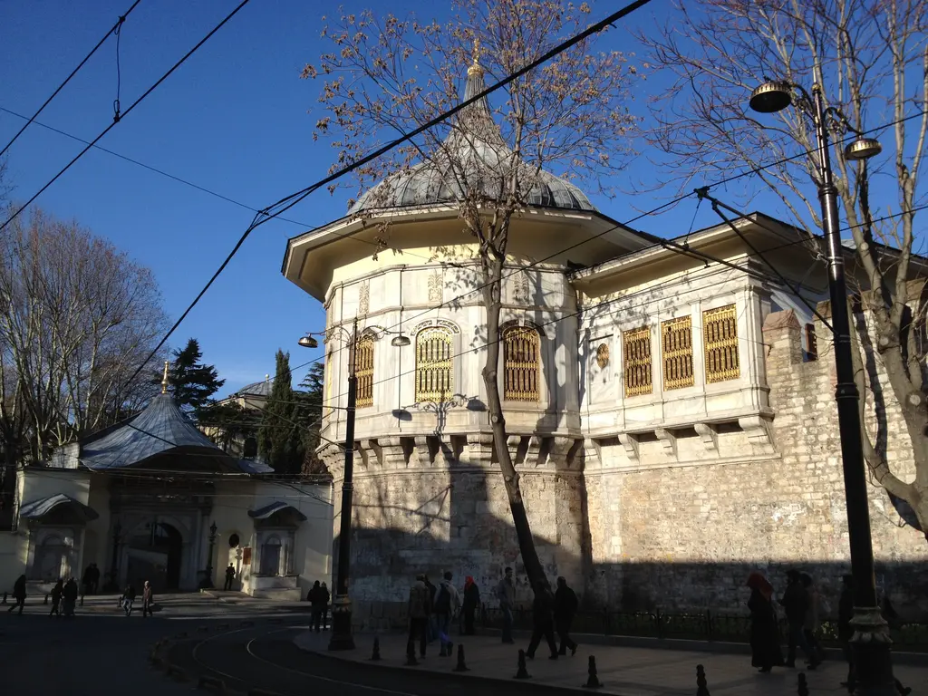Kışın Alay Köşkü; mermer salon ve sur üstündeki kanat, solda Gülhane Parkı kapısının kubbesi, yapraksız ağaçlar ve yürüyen insanlar.