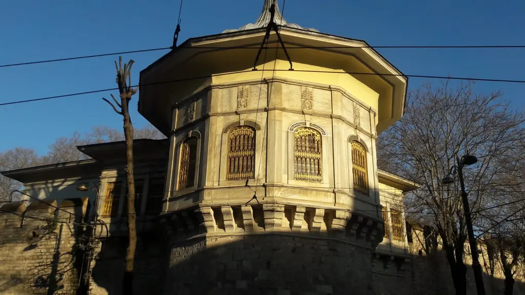 Akşam güneşinde Alay Köşkü; altın rengine bürünen mermer salon, kafesli pencereler, taş konsollar, gölgede kalan burç ve koyu mavi gök.
