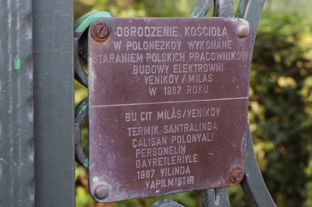 Polonezköy'de yeşil boyalı demir çite vidalanmış bakır plaket; üst yarısında Lehçe, alt yarısında Türkçe yazı.