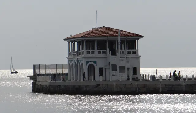 Kadıköy'de Moda İskelesi; kiremit çatılı iki katlı bina, denize uzanan taş iskele yolu ve güneşte parlayan deniz.