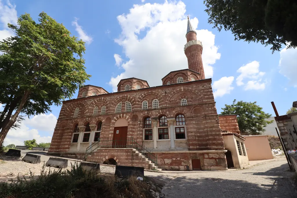 Fatih'te Vefa Kilise Camii'ne güneybatıdan bakış; beş bölümlü kemerli cephe, mermer sütunçeler, ortada ahşap kapıya çıkan taş merdiven, arkada kubbeler ve tuğla minare.